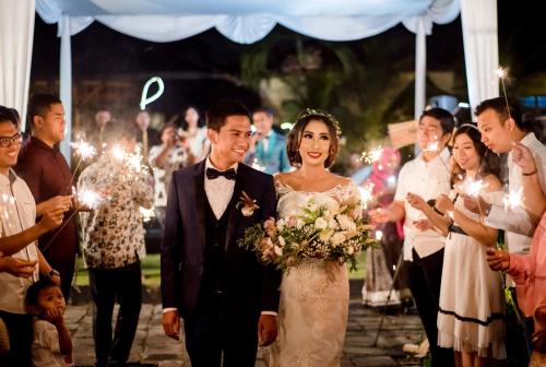 a bride and groom walking down the aisle with sparklers at Tasneem Hotel Malioboro Yogyakarta in Yogyakarta