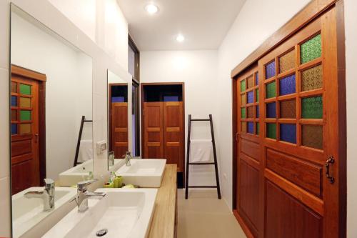 a bathroom with two sinks and a wooden door at Jasmine Hills Lodge in Doi Saket