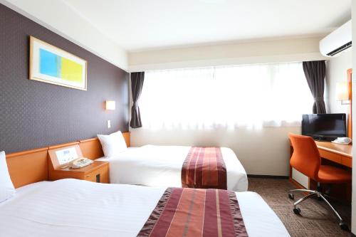 a hotel room with two beds and a desk at Hotel Hokke Club Fukuoka in Fukuoka