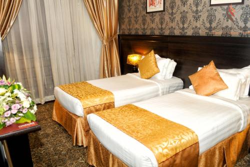 a hotel room with two beds and a table with flowers at Deyar Al Eiman Hotel in Al Madinah