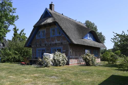 ein altes Haus mit einem Strohdach auf einem Feld in der Unterkunft Fachwerkhäuser Gager Haus „Strate“ in Gager