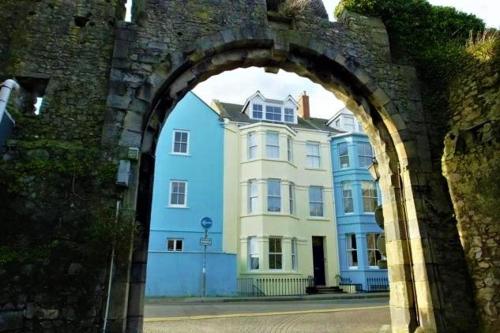 a large blue and white house behind an archway at Spetchley House in Tenby