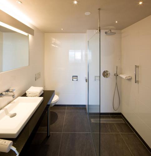 a bathroom with a glass shower and a sink at Van der Valk Hotel Stein Urmond in Urmond