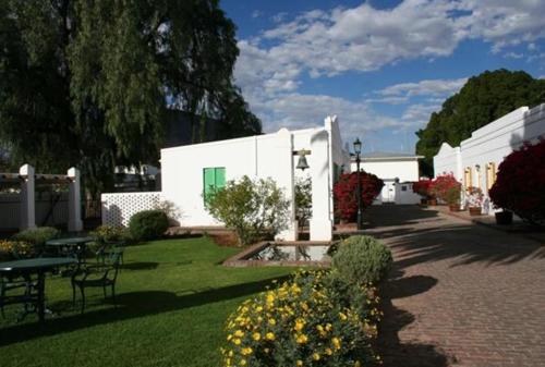 a white building with a table and chairs in a yard at Karoopark Guest House in Graaff-Reinet