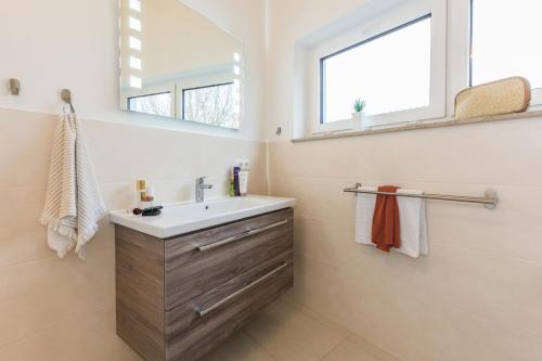 La salle de bains est pourvue d'un lavabo et d'un miroir. dans l'établissement Strandhaus Lindenstraße, à Zingst