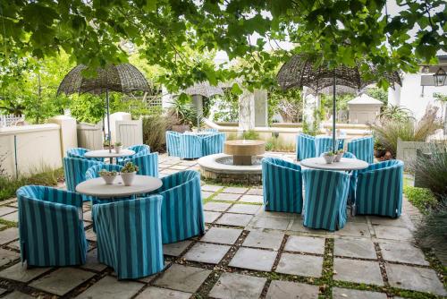 a group of blue chairs and tables with umbrellas at Hout Bay Manor in Hout Bay