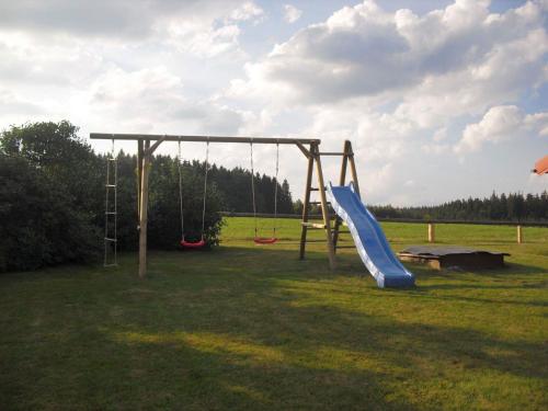 a playground with a slide in a field at Ferienhaus Schallerhof in Kupferberg