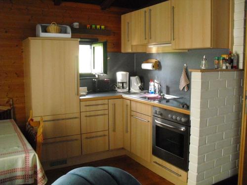 a small kitchen with wooden cabinets and a stove at Ferienhaus Schallerhof in Kupferberg