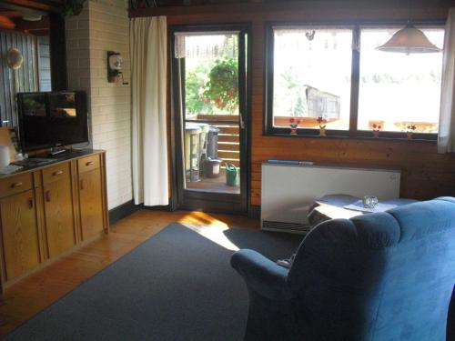 a living room with a blue couch and a television at Ferienhaus Schallerhof in Kupferberg