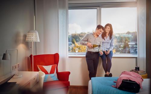two people are standing in a room with a window at WestCord Hotel Delft in Delft