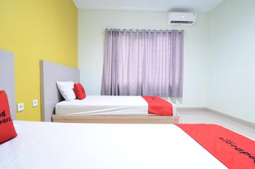 a bedroom with two beds and a window at RedDoorz near Museum Keraton Surakarta in Solo
