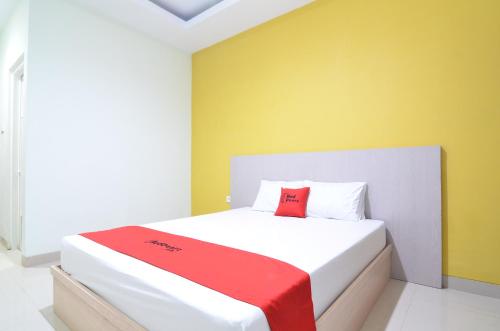 a bedroom with a bed with a red pillow on it at RedDoorz near Museum Keraton Surakarta in Solo