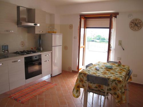 uma cozinha com uma mesa e um frigorífico branco em Casa dei Girasoli - Formia centro em Formia