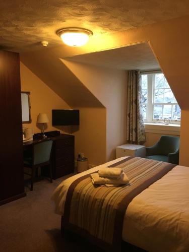 a bedroom with a bed and a desk and a window at Crown Guest House in Aberdeen