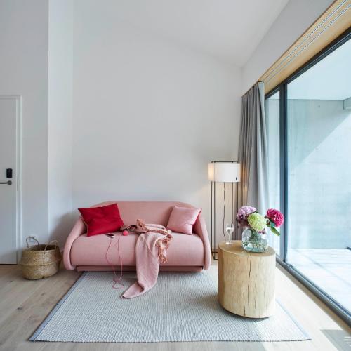 a pink couch in a living room with a table at meinwolfsburg hotel auf dem rittergut vormals Yard Boarding Hotel in Wolfsburg