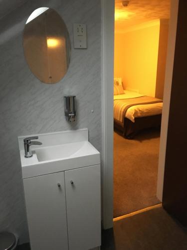 a bathroom with a sink and a bedroom with a bed at Crown Guest House in Aberdeen
