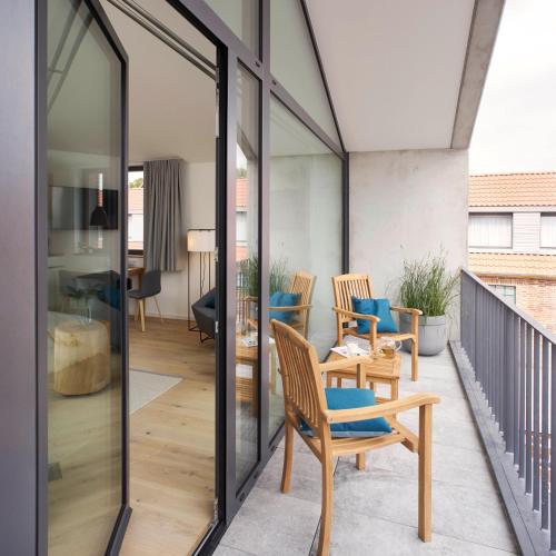 Zimmer mit Glastüren und Stühlen auf einem Balkon in der Unterkunft Yard Boarding Hotel Wolfsburg in Wolfsburg