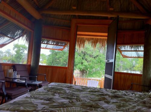 a bedroom with a bed and a table and windows at Everglades Chickee Cottage & Bungalow - Ochopee in Ochopee