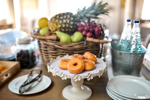 Una mesa con un plato de donas y una cesta de fruta. en Hotel Oromana, en Alcalá de Guadaira