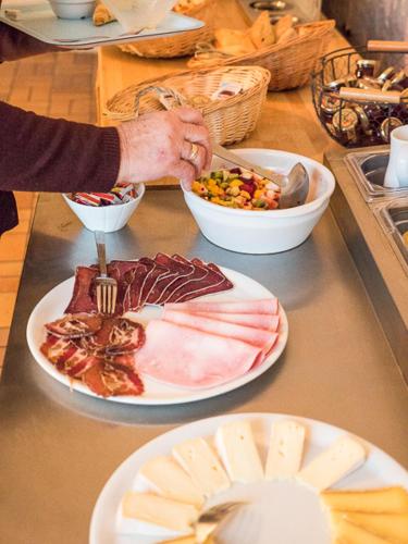 een persoon die eten op een aanrecht met borden voedsel bij Hôtel Restaurant Les Alpins in Saint-Julien-en-Beauchêne