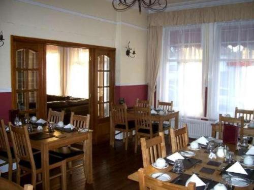 una sala da pranzo con tavoli e sedie in legno e finestre di Kingsley Hotel a Bournemouth