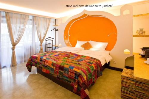 a bedroom with a large bed with an orange headboard at PLAZA INN stays design Dortmund in Dortmund