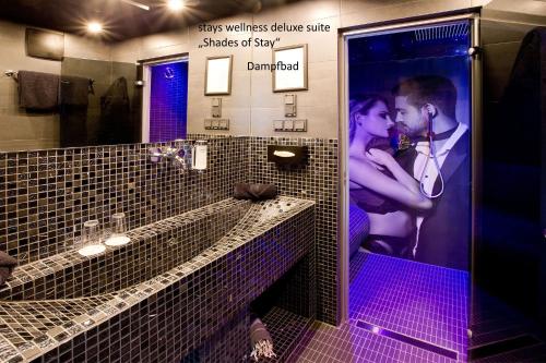 a couple kissing in a bathroom with purple lights at PLAZA INN stays design Dortmund in Dortmund