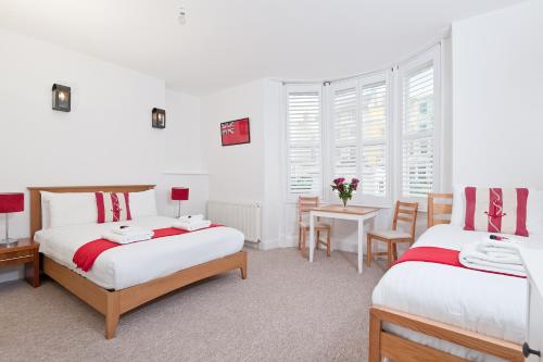two beds in a room with a table and chairs at Hamptons Brighton in Brighton & Hove