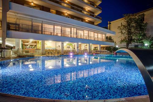 ein Schwimmbad vor einem Gebäude in der Nacht in der Unterkunft Hotel Gambrinus - Valentini Family Village in Bellaria-Igea Marina