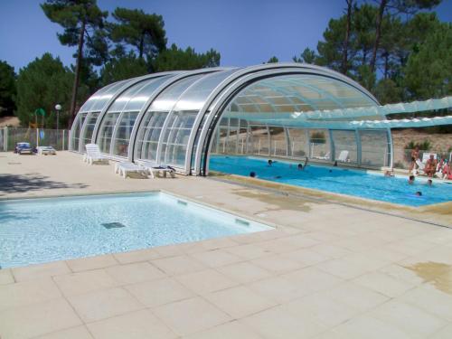 une piscine avec un grand bâtiment avec une piscine dans l'établissement Village Vacances Les Dunes - Domaine de Bombannes, à Carcans