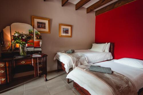 a room with two beds and a red wall at Wildebraam Berry Estate in Swellendam