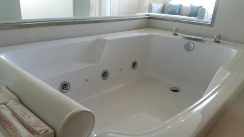 a white bath tub in a bathroom with a window at The Beverly Hills Hotel in Nakhon Ratchasima