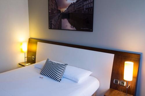 a bedroom with a white bed with a pillow on it at Hotel Mercure Rennes Cesson in Cesson-Sévigné