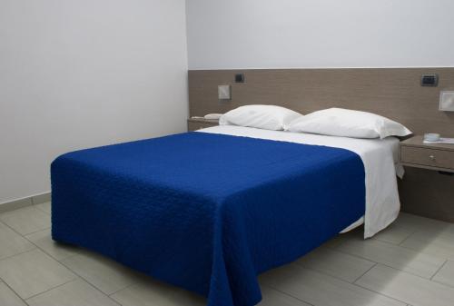 een bed met een blauwe deken en witte kussens bij Hotel Cristian in Giugliano in Campania