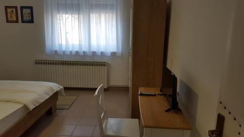 a bedroom with a bed and a tv and a window at Apartmani Ana in Szlatina