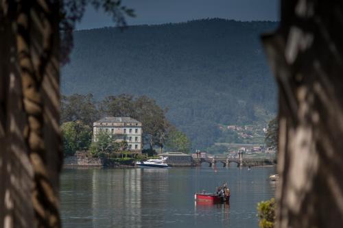 a boat on a river with a building in the background at Hostal Antolín in Redondela
