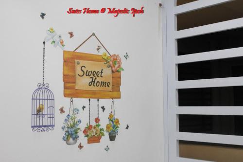 a sign on a wall with flowers and a bird cage at H2H - Swiss Home - Majestic Ipoh in Ipoh