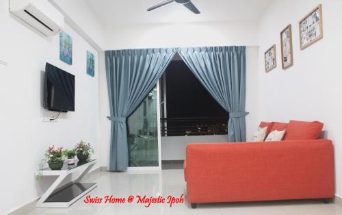 a living room with a red couch and a window at H2H - Swiss Home - Majestic Ipoh in Ipoh