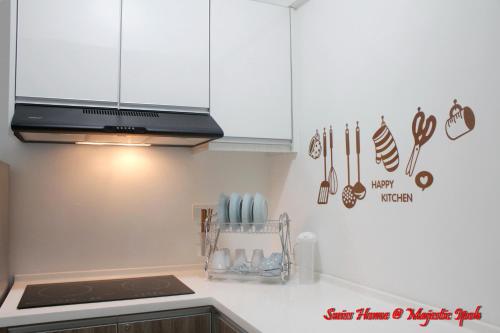 a kitchen with white cabinets and utensils on the wall at H2H - Swiss Home - Majestic Ipoh in Ipoh