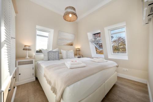 1 dormitorio blanco con 1 cama blanca grande y 2 ventanas en Villa Strandblick 12, en Zingst