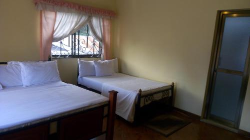 two beds in a small room with a window at Bright Star Hotel in Arusha