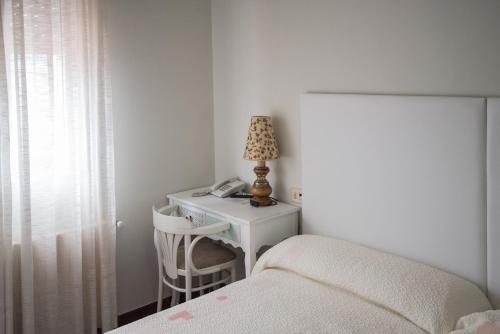 a bedroom with a bed and a desk with a lamp at Hostal Antolín in Redondela