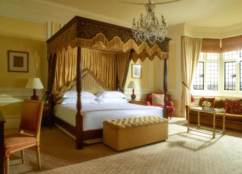 a bedroom with a large bed and a chandelier at Danesfield House Hotel And Spa in Marlow