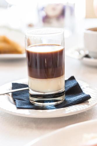 a glass of coffee on a plate on a table at Hostal Antolín in Redondela