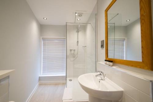 a white bathroom with a sink and a shower at The Town House by Innkeeper's Collection in Norwich