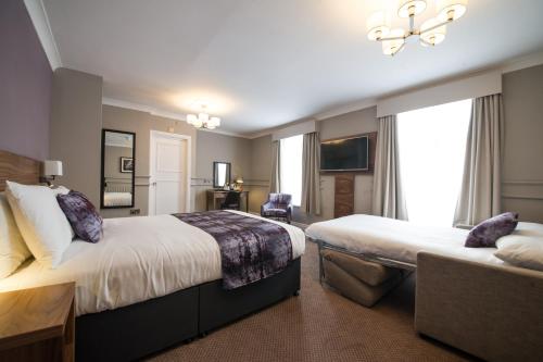 a hotel room with two beds and a television at The Town House by Innkeeper's Collection in Norwich