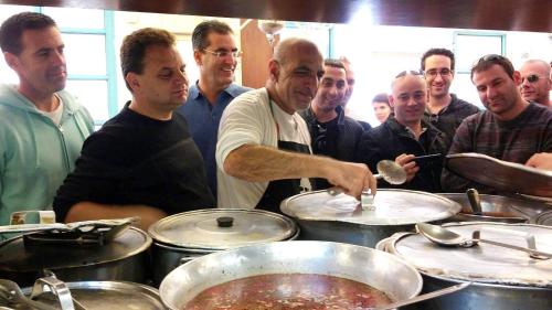 a man preparing food in front of a group of people at Modern Home In The Heart of Nachlaot in Jerusalem