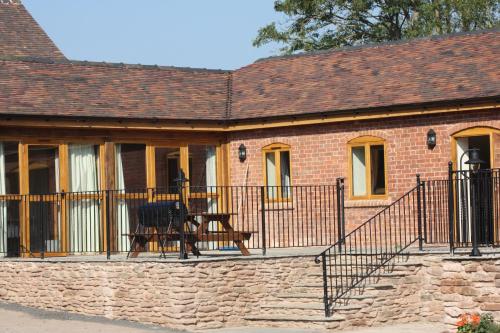 a brick house with a balcony with a table on it at The Stables in Bromyard