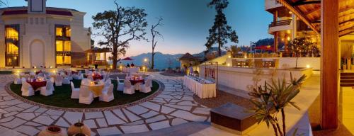 un locale con tavoli e sedie e un edificio di Royal Orchid Fort Resort Mussoorie a Mussoorie