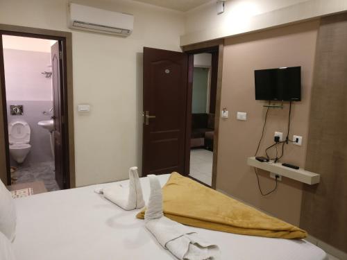 ein Schlafzimmer mit einem Bett und einem TV sowie ein Badezimmer in der Unterkunft Hotel Silver Palace in Haldwani-Kathgodam